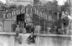 Eine Weingesellschaft mit Kind und Kegel posiert dem Fotographen vor dem neuerbauten Torggelhaus, dem heutigen Gasthaus Zeigerle.